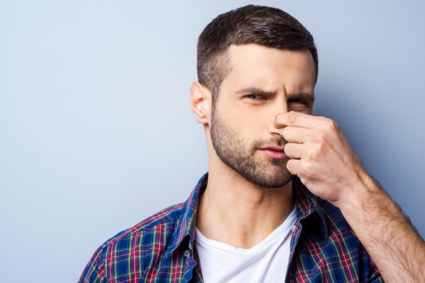 man pinching his nose due to oil smell
