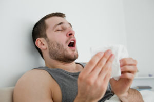 man sneezing due to poor indoor air quality