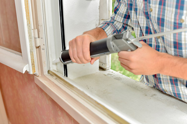 image of a homeowner sealing window to prevent heated air from escaping