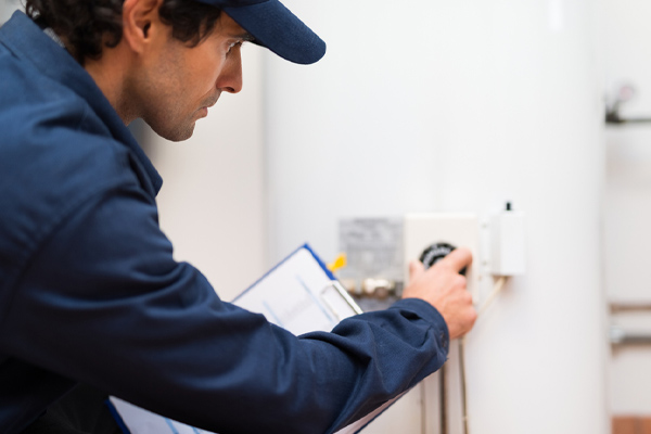 plumber adjusting water heater thermostat