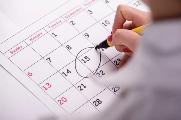 Woman encircling a date on a calendar depicting planning routine maintenance