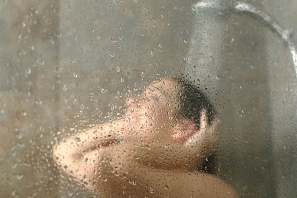 image of a homeowner taking a shower adding to high humidity levels indoors