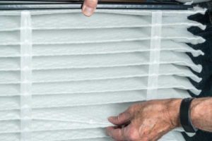 image of a senior man replacing his furnace filter