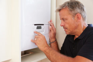 boiler technician servicing a domestic boiler and setting boiler temperature