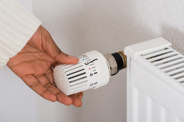 homeowner adjusting radiator temperature of boiler