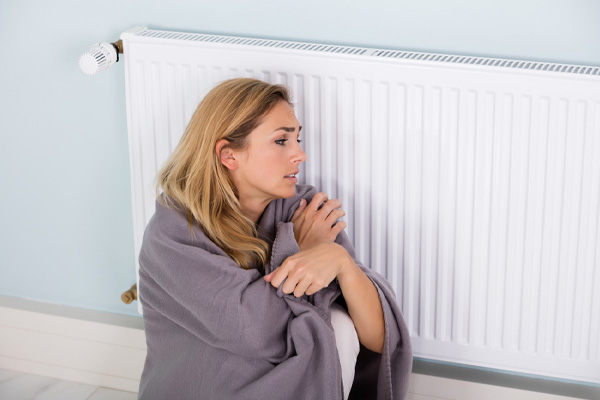 image of a homeowner sitting by radiator due to cold spots in house