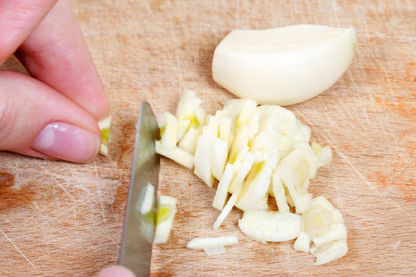 image of a homeowner cooking with garlic depicting odor removal with hvac mechanical ventilation