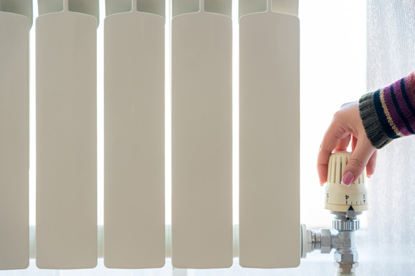 image of homeowner adjusting hot water radiator