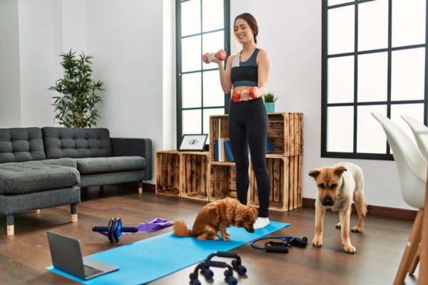 Woman happily exercising indoors with her dogs depicting good indoor air quality