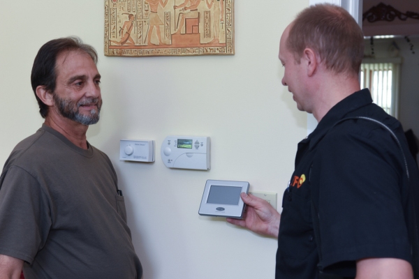PFO Heating & Air Conditioning HVAC technician showing thermostat upgrade to a client