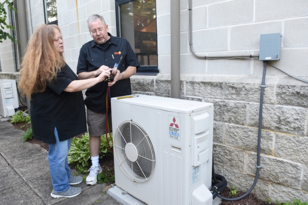 PFO Heating & Air Conditioning HVAC technician showing a homeowner final checks after installing ductless AC