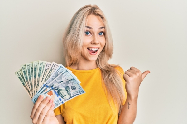 woman holding dollar bills and doing a thumbs up depicting affordability of heating oil