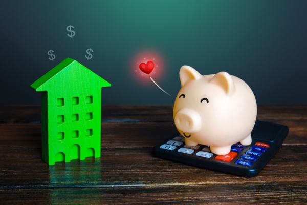 image of a piggy bank on top of a calculator beside a miniature house figure depicting Financial Advantages of heating oil