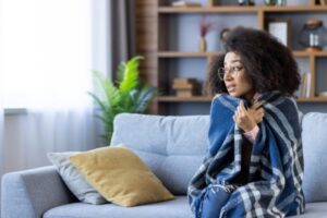 woman sitting on a couch wrapped in a blanket due to furnace malfunction