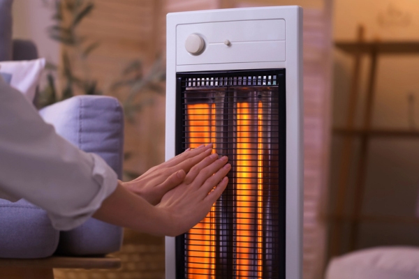 woman warming hands by the electric heater