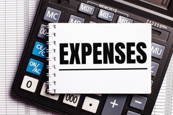 expenses word on a notebook on top of a calculator