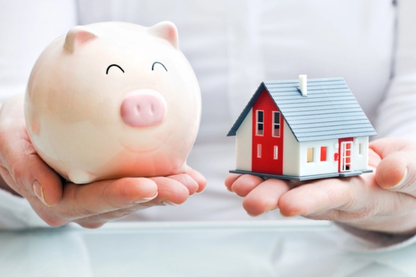Hands holding piggy bank and miniature house model on each hand depicting Financial Benefits for Homeowners of heating installation