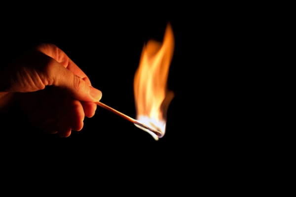 hand holding a matchstick depicting power interruption
