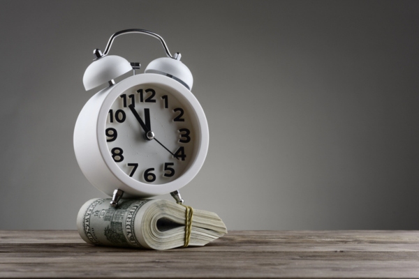 alarm clock on top of dollar bills depicting saving time and money