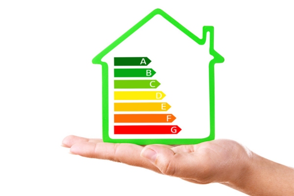 hand balancing energy efficiency scale inside a miniature house outline