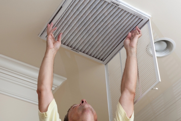 homeowner installing HVAC filter in the ceiling
