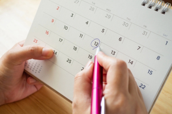 female's hand holding and encircling a desk calendar depicting Skipping Routine Air Conditioner Maintenance