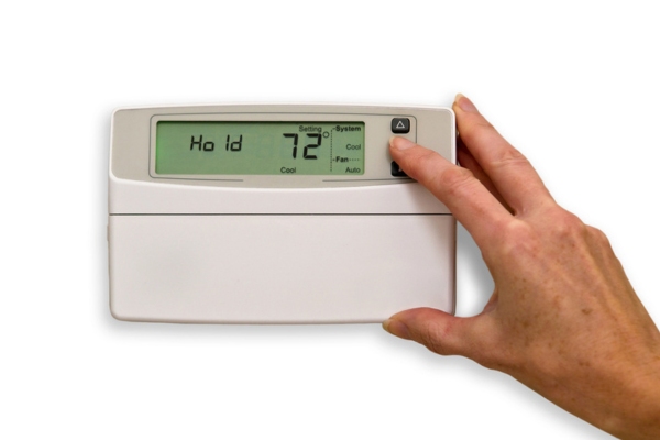 homeowner adjusting thermostat for warmer weather