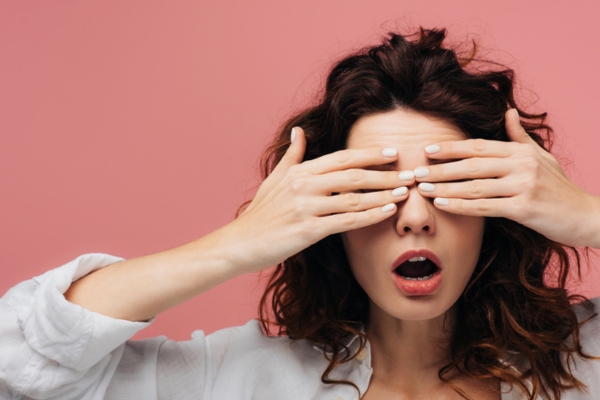 woman covering her eyes with her hands depicting Overlooking Early Signs of Air Conditioner Problems