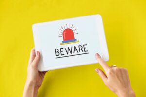woman's hands holding a smart tablet with BEWARE on display depicting air conditioning scams