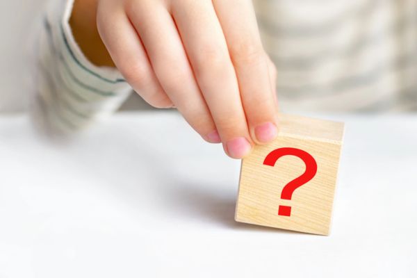 hand holding wooden cube with red question mark depicting Affordable Heating Oil FAQs